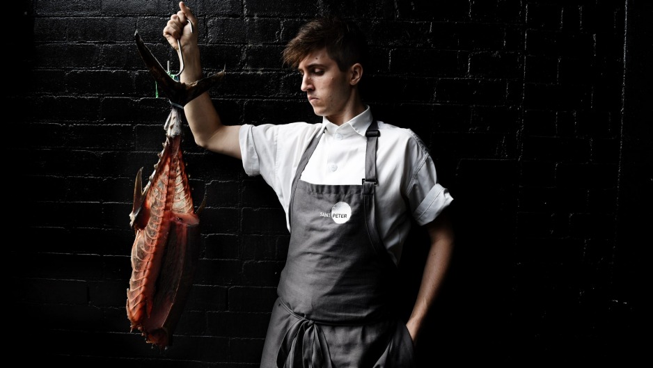 Chef Josh Niland wearing an apron, holding a large fish