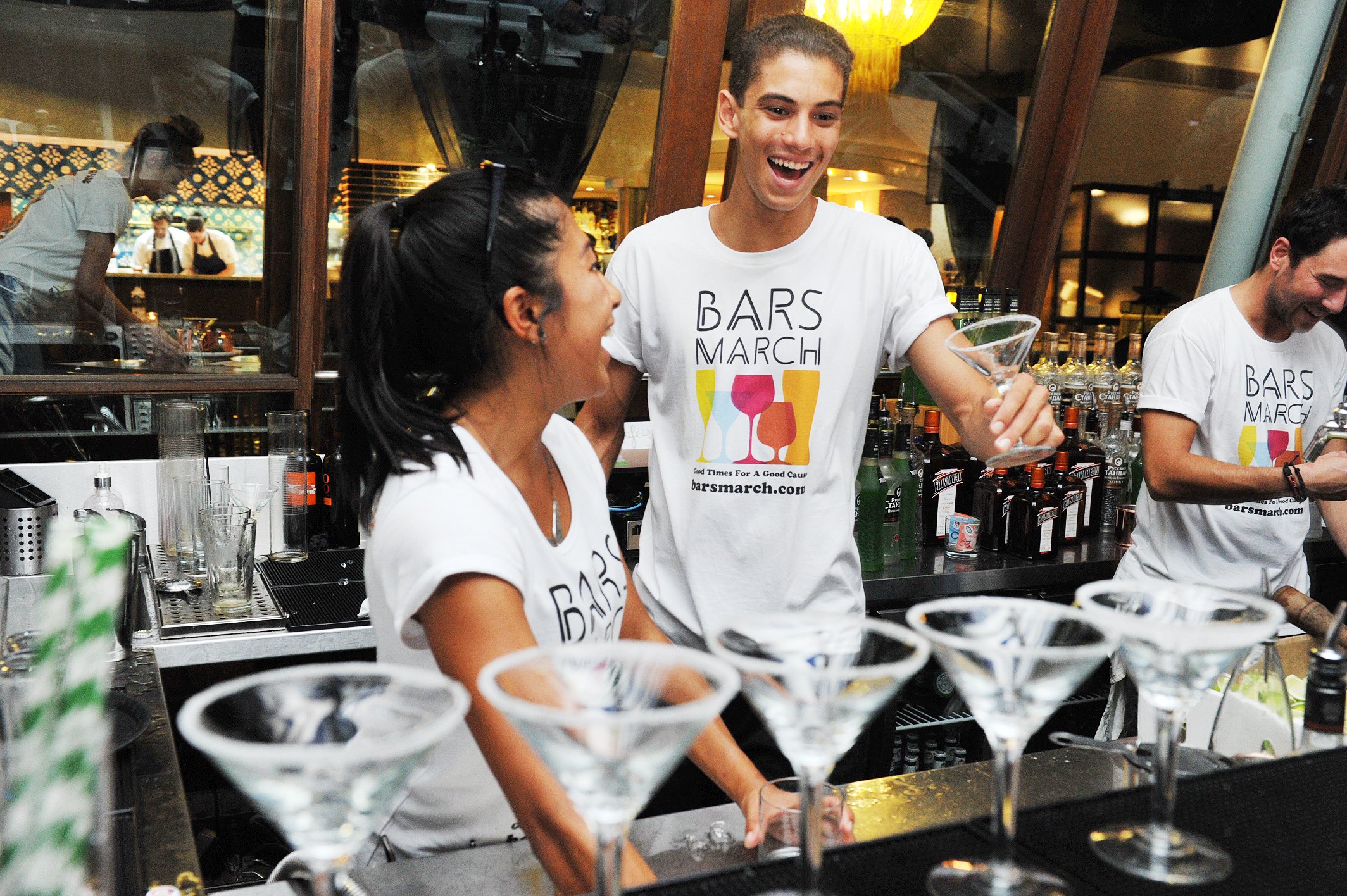 Two bartenders preparing a round of martinis at a bar