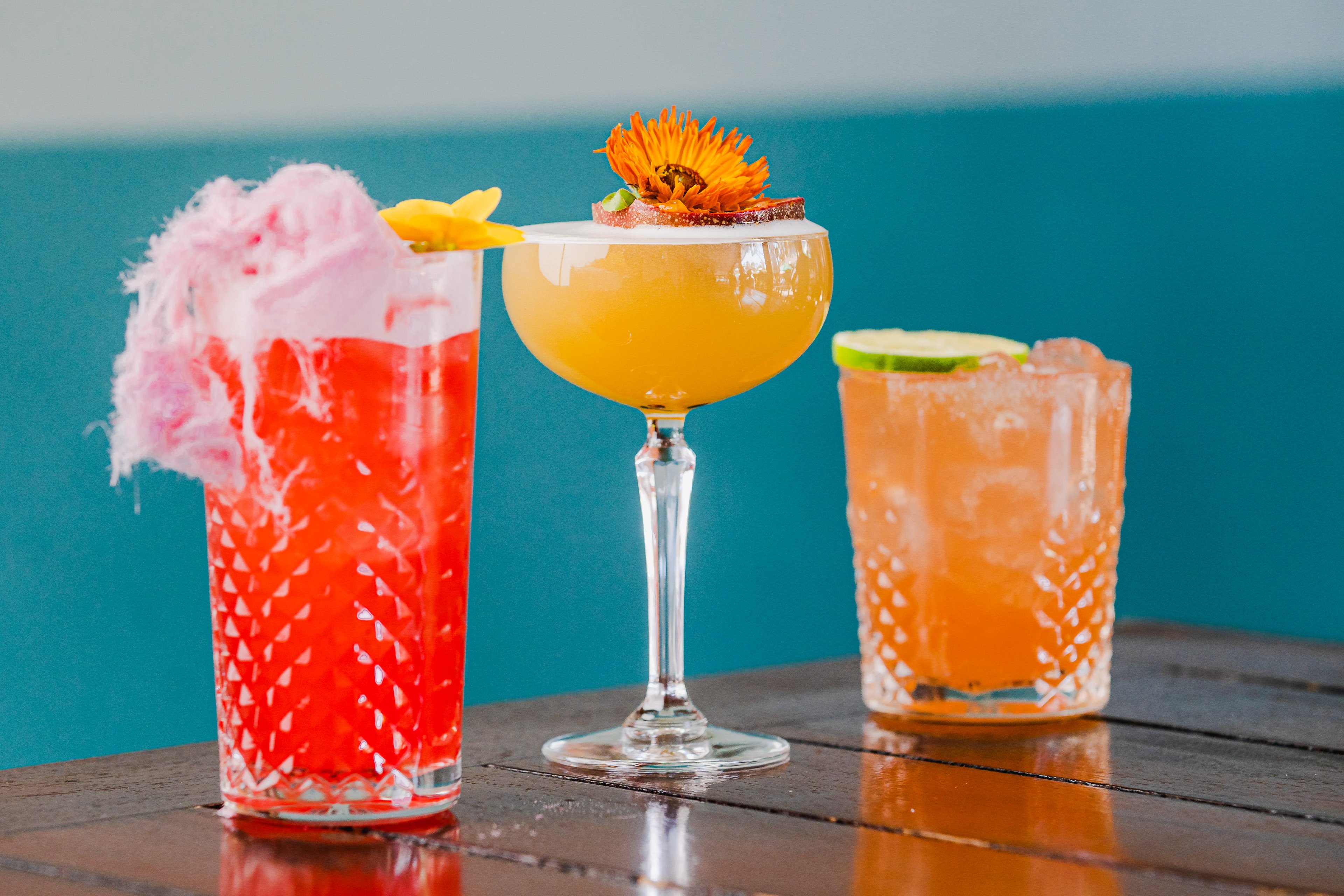Three vibrant cocktails with an out of focus blue background