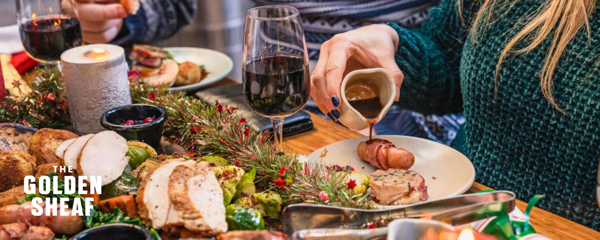 Table filled with Christmas decorations, red wine and a roast dinner feast