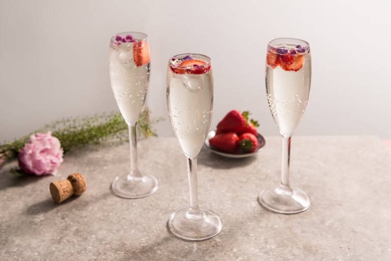 Elderflower prosecco cocktails topped with berries in flute glasses