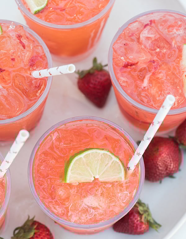 Strawberry tequila sodas topped with lime with paper straws