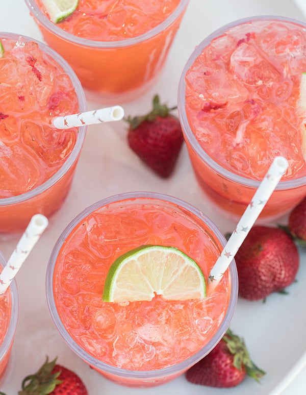 Strawberry tequila sodas topped with lime with paper straws